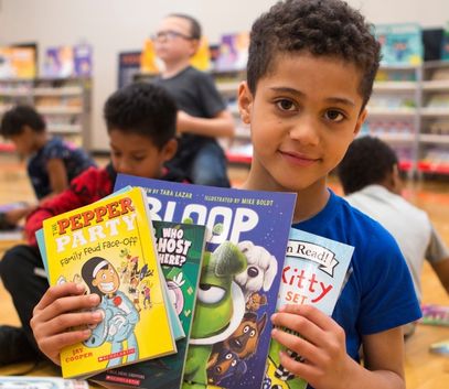 Boy with books received through the If You Give A Child A Book ... campaign